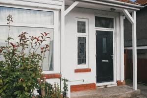 una casa blanca con una puerta negra y una planta en 39 Court Rd en Bristol