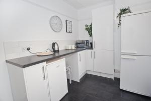 a kitchen with white cabinets and a clock on the wall at Druids Hill in Bristol