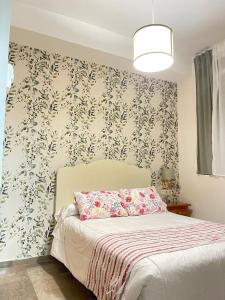 Hotel Corona de Atarfe في Atarfe: غرفة نوم مع سرير وورق جدران