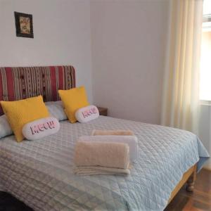 1 cama con 2 almohadas y toallas en Piso de Kireyna, en Cusco