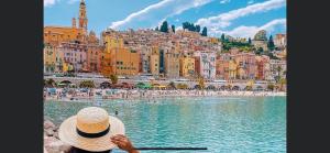 a person in a straw hat sitting on a boat in a body of water at Menton centre Vue imprenable sur mer et jardin Biovès in Menton