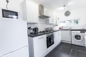 a kitchen with white cabinets and a washer and dryer at Three Bed - Suitable for Contractors- Large Groups in Bristol