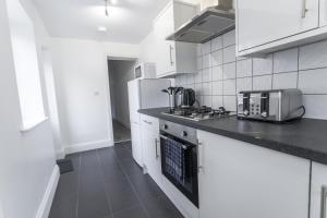 a kitchen with white appliances and a black counter top at Three Bed - Suitable for Contractors- Large Groups in Bristol