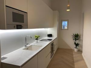 uma cozinha branca com dois lavatórios e uma televisão em Citylux Verdandi em Turku
