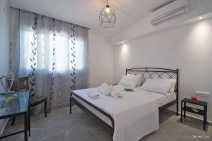 um quarto com uma cama com lençóis brancos e almofadas em Oresti's Villa Near Airport & Beach em Artemida