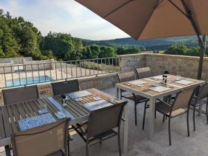 a patio with two tables and chairs and an umbrella at Domaine de Fleurie in Tursac