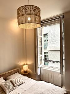維特雷的住宿－Les Suites de la Tour d'Embas，一间卧室设有一张床、一个窗户和一个吊灯。