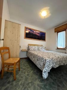 a bedroom with a bed and a chair at Dolomitihouse AUNER in Fiera di Primiero +45 photos
