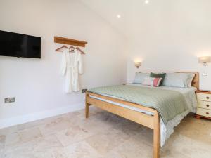 een slaapkamer met een bed en een tv aan de muur bij The Pennymoor in Tiverton