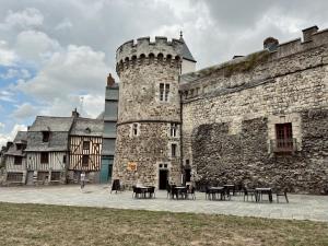 un château avec des tables et des chaises en face de celui-ci dans l'établissement Les Suites de la Tour d'Embas, à Vitré