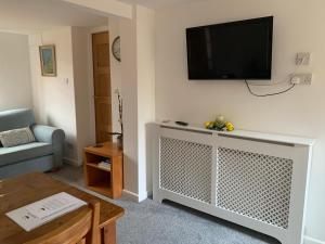 a living room with a flat screen tv on the wall at One bedroom self contained annex with own bathroom, sitting room and kitchenette in Emsworth