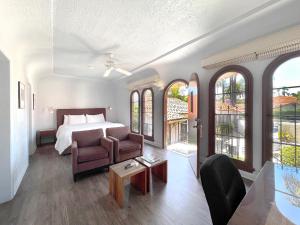 a bedroom with a bed and a couch and a chair at Casa Del Mar Inn in Santa Barbara