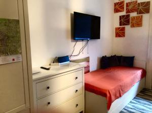a bedroom with a bed and a dresser with a tv on the wall at Wiesbaden Mitte in Wiesbaden