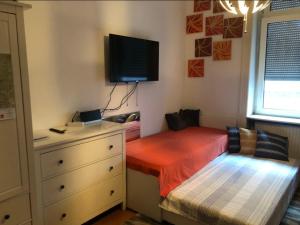 a bedroom with a bed and a dresser with a tv on the wall at Wiesbaden Mitte in Wiesbaden