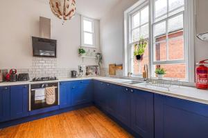 a large kitchen with blue cabinets and a sink at Luxury 2 bed apartment in the heart of Chester in Chester