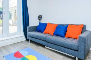 a couch with orange and blue pillows in a room at 4 Freeland Buildings in Bristol