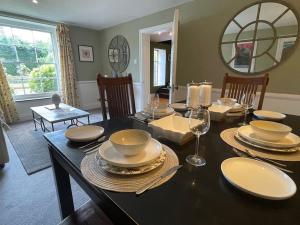 uma sala de jantar com uma mesa com pratos e copos de vinho em Stylish 2-bed cottage with secure parking em Winforton