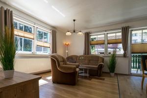 ein Wohnzimmer mit 2 Stühlen, einem Tisch und Fenstern in der Unterkunft Ferienanlage Zum Wildbach Schierke in Schierke