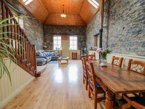 a living room with a wooden table and a stone wall at Coach House in Portlaoise