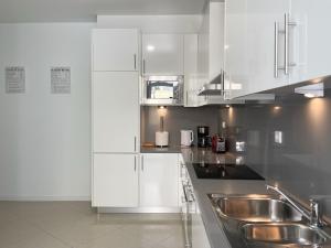 La cuisine est équipée de placards blancs et d'un évier en acier inoxydable. dans l'établissement Dreamy Alameda Apartment, à Lisbonne