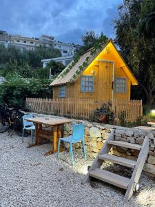 una pequeña casa amarilla con mesa y sillas en Camping Albania-Secret Village Den, en Sarandë