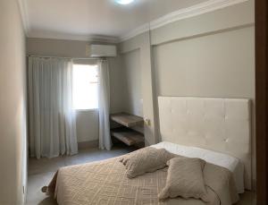 een witte slaapkamer met een bed en een raam bij Ap à 170m do mar, Praia dos Ingleses in Florianópolis