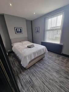 a bedroom with a large bed with white sheets at Harrington House in Cleethorpes