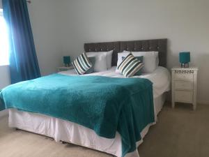 ein Schlafzimmer mit einem großen Bett mit einer blauen Decke in der Unterkunft Sea Bean 2 Bedroom House Manorbier Tenby Pet Friendly in Manorbier
