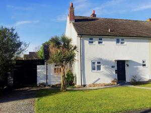 a white house with a dog sitting in the front yard at Sea Bean 2 Bedroom House Manorbier Tenby Pet Friendly in Manorbier