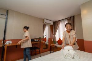 Dos mujeres de pie en una habitación de hotel con una cama en Hoianese Center Hotel - Truly Hoi An en Hoi An
