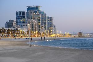 a beach with tall buildings in the background with people on it at Selina Frishman Tel Aviv in Tel Aviv