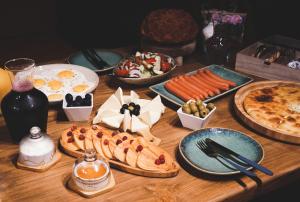 a wooden table with plates of food and a pizza at Hotel Darchi Kazbegi in Stepantsminda