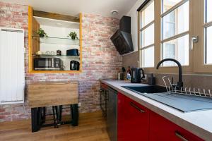 a kitchen with red cabinets and a brick wall at Dijon centre historique, superbe studio à 2 pas des trams in Dijon