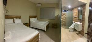 a small bedroom with two beds and a shower at Lomas Hotel in San José de Ocoa