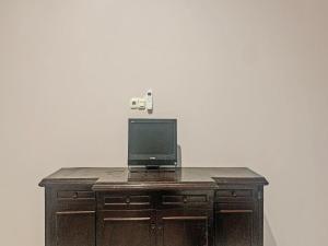 einen hölzernen Schreibtisch mit einem TV darüber in der Unterkunft OYO 91657 Penginapan Radja Jeneponto in Pannara