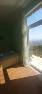 1 dormitorio con ventana grande con cama y vistas en Abramichi Guest House, en Signagi