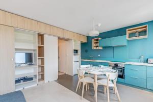 kuchnia z niebieskimi szafkami oraz stołem i krzesłami w obiekcie Appartement Cyan - Welkeys w mieście Lyon