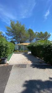 a yard with a building and some bushes and trees at Bungalow de luxe de 60m2 dans camping 5 étoiles in Puget-sur Argens