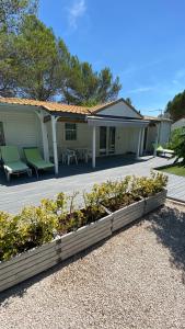 a house with a porch with green chairs and plants at Bungalow de luxe de 60m2 dans camping 5 étoiles in Puget-sur-Argens