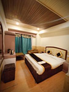a bedroom with a large bed with green curtains at Shorya Regency in Shimla
