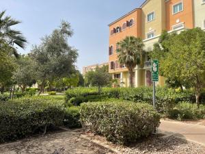 a building in a park with trees and bushes at Birchfort - Newly renovated unique 1 bedroom apartment in Dubai