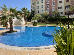 a large blue swimming pool with palm trees and buildings at Birchfort - Newly renovated unique 1 bedroom apartment in Dubai