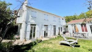 Biały dom z krzesłem na dziedzińcu w obiekcie Très jolie Villa Bianca, maison avec jardin privé à Deauville w mieście Deauville