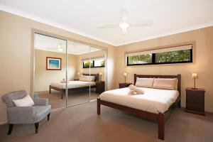 1 dormitorio con cama, silla y espejo en Panorama at Jervis Bay I Pet Friendly I 15 Mins to Hyams Beach en Bewong