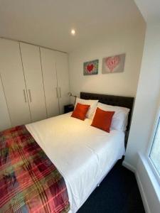 - une chambre avec un lit blanc et deux oreillers orange dans l'établissement Beachside House, à Brighton et Hove