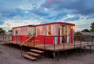 a red tiny house sitting on top of a wooden deck at El Cosmico in Marfa
