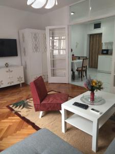 uma sala de estar com uma cadeira vermelha e uma mesa branca em Palace Luxury Apartments The Heart of Belgrade em Belgrado