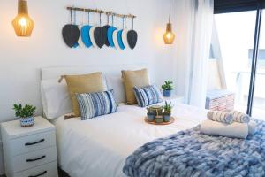 een slaapkamer met een groot wit bed met blauwe kussens bij Iconic Sea Views Luxury Apartment in Puerto Marino