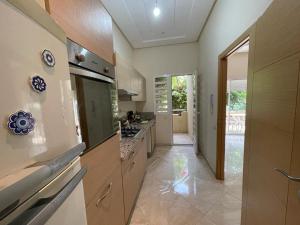 a large kitchen with wooden cabinets and a large window at The garden corner in Bouznika