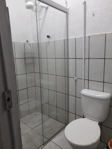 a bathroom with a toilet and a glass shower stall at Pousada Solar Encanto do Marajó in Soure